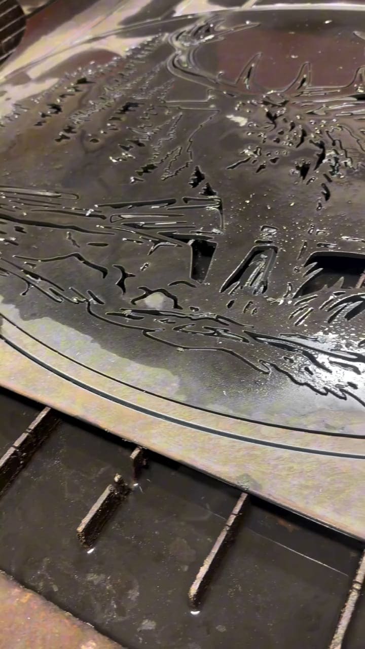 A steel plate on the bench with a shape freshly cut through it by the plasma cutter