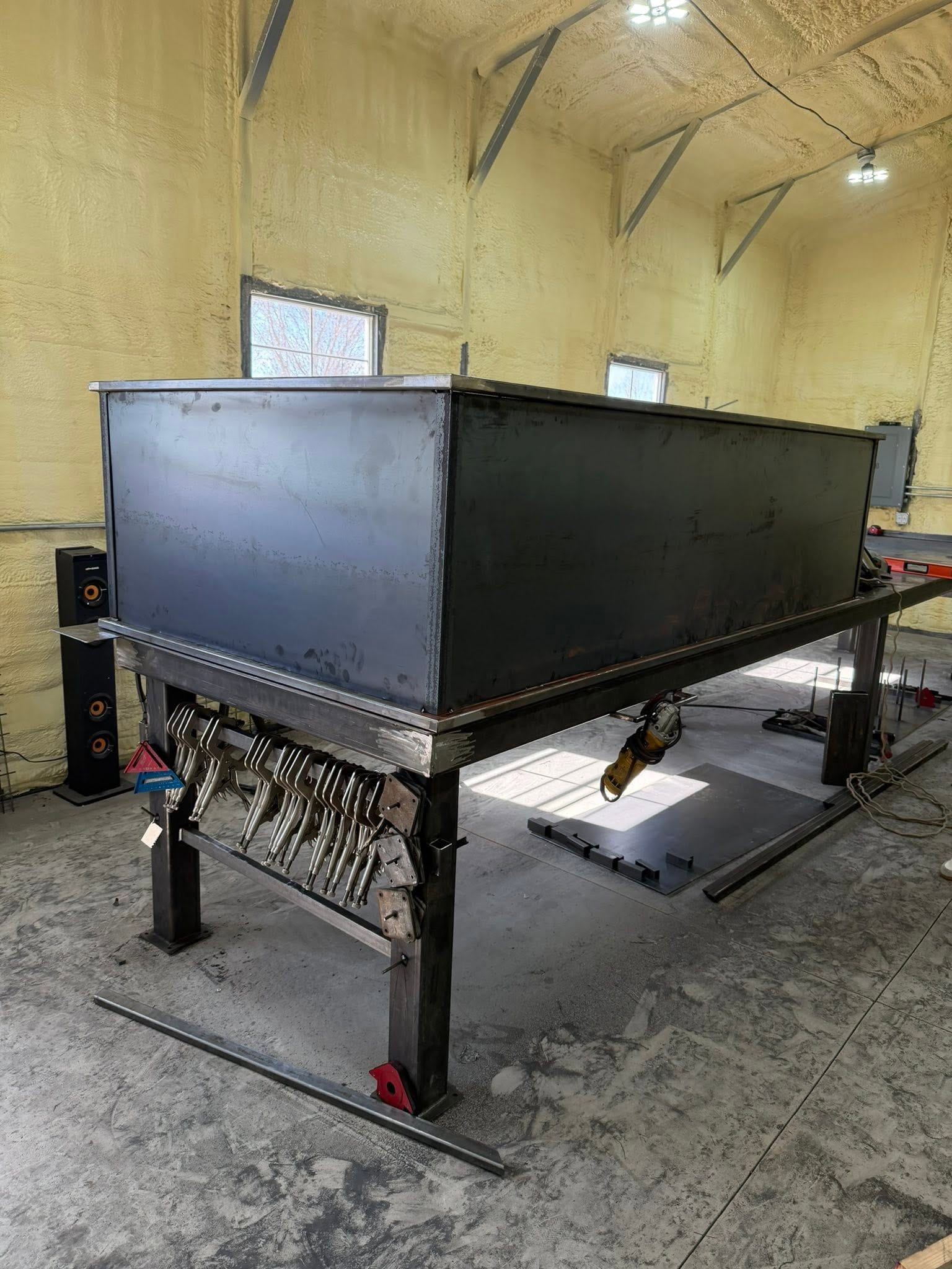 A large steel garden box mid-fabrication on the welding table in the shop