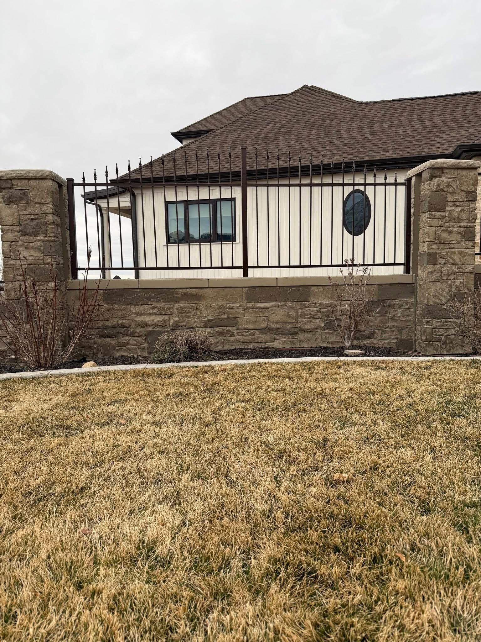 Ornamental iron fence with spear finials between cut stone columns